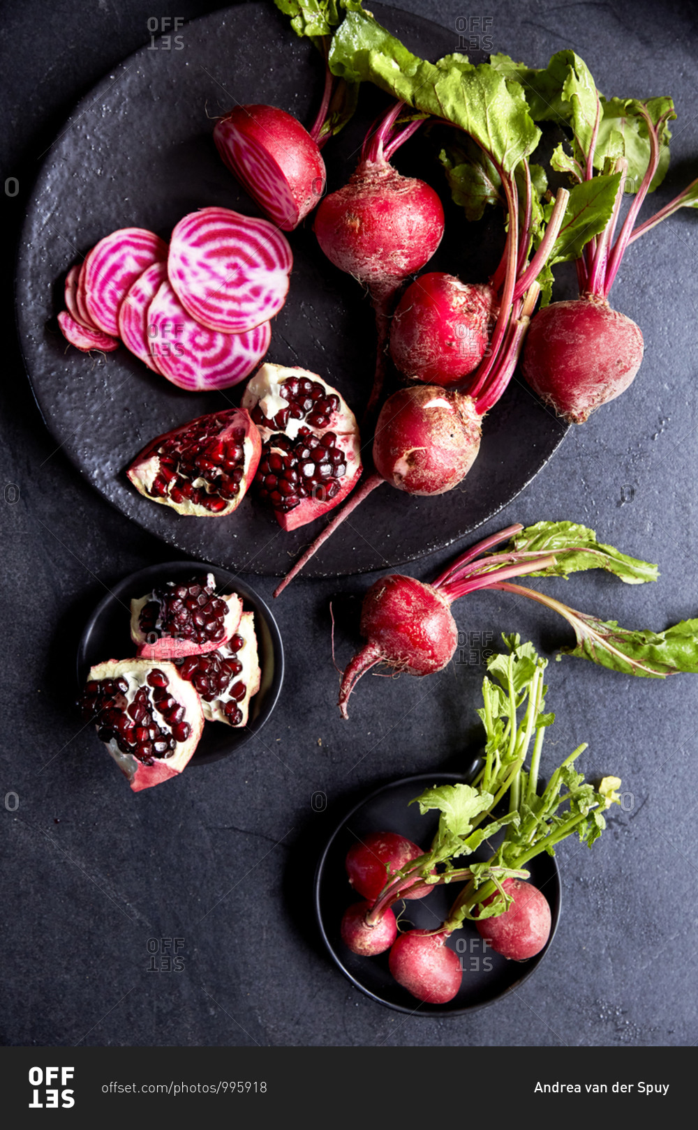 A bunch of candy stripe beetroot and sliced pomegranate on plates