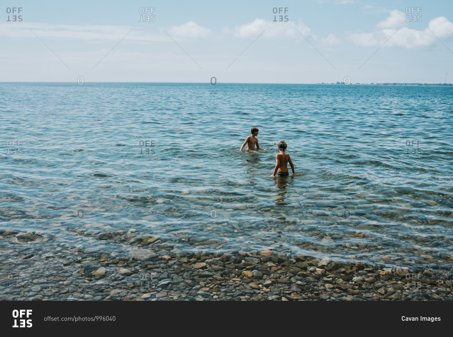 Two boys wading in lake ontario on a summer day.