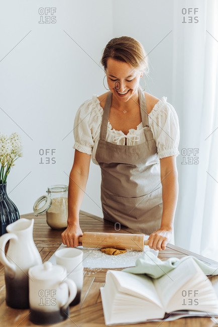Woman rolling dough for cookies standing at domestic kitchen