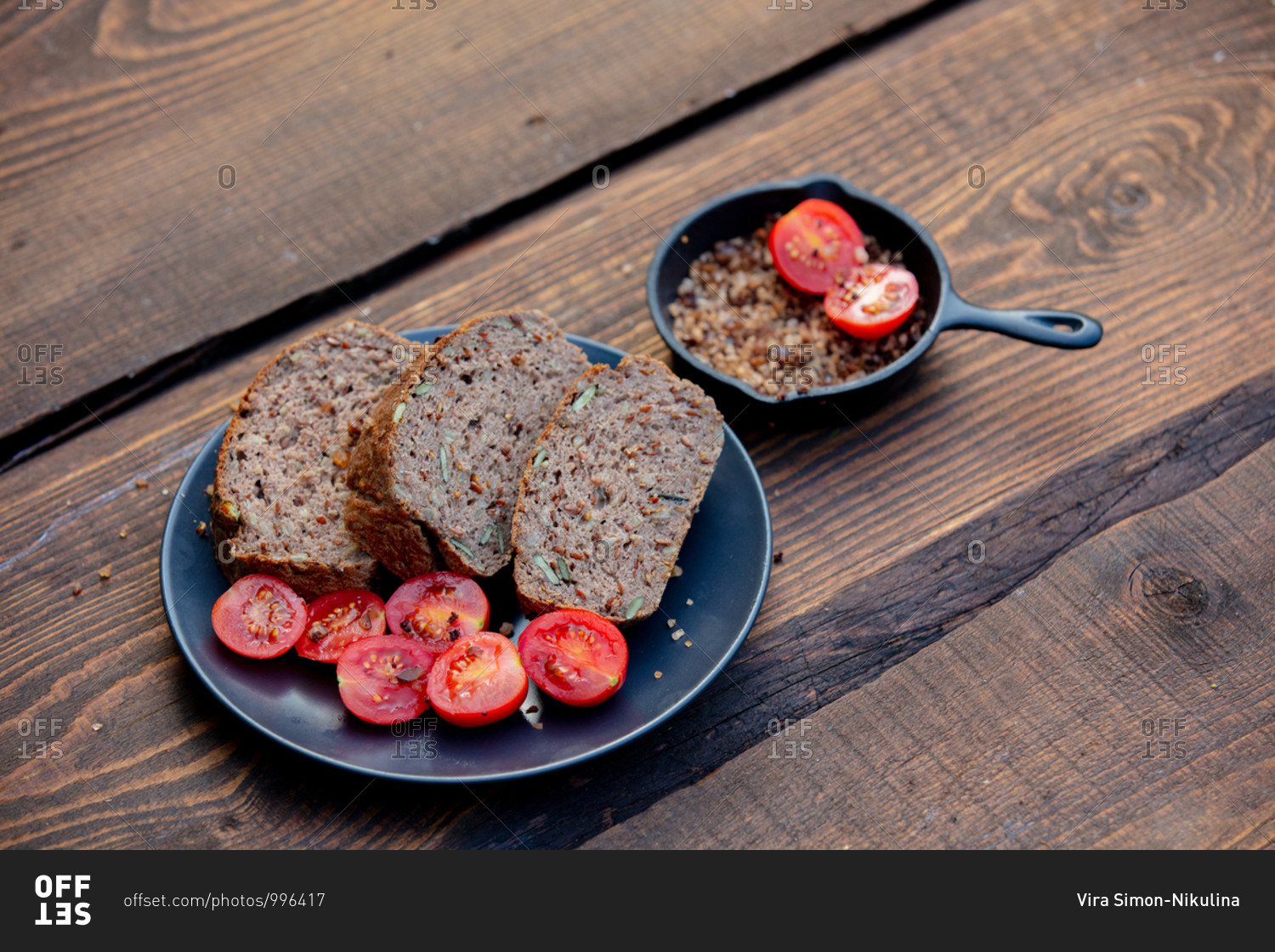 Gluten-free bread with pumpkin seeds, tomatoes and salt on wooden table
