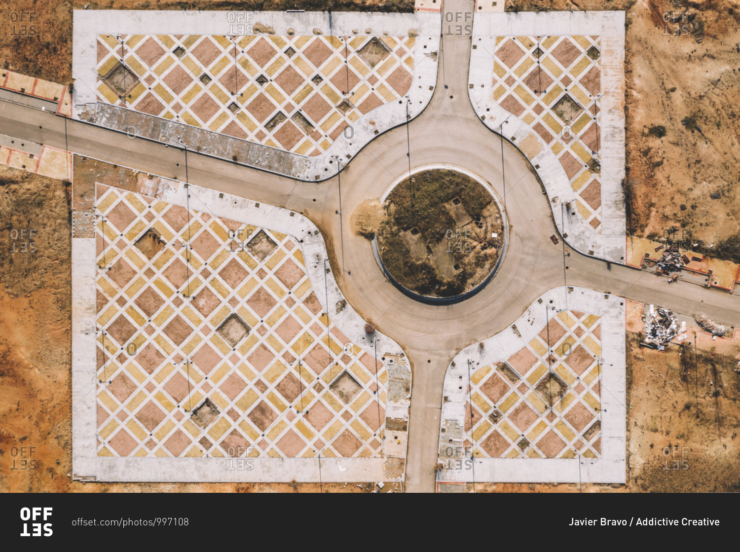 From above aerial view of road intersection with traffic roundabout in dry terrain with ornamental infrastructure