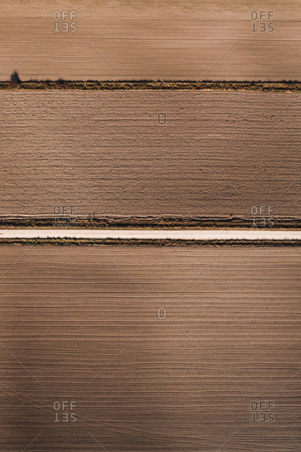 From above aerial view of straight road going through agricultural field in rural area in summer day
