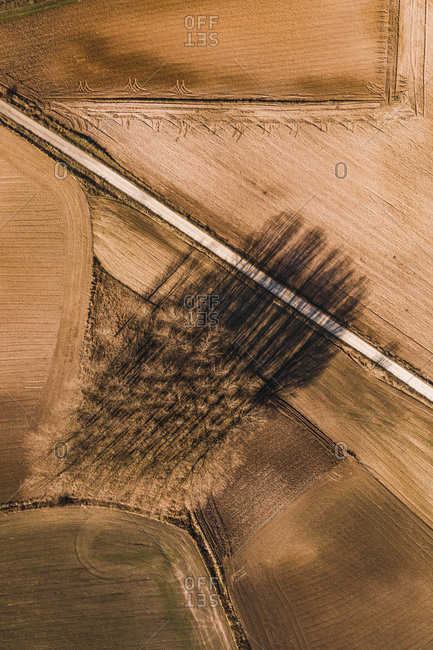 From above aerial view of straight road going through agricultural field in rural area in summer day
