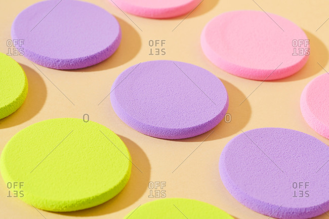 Round colorful makeup sponges on a neutral background
