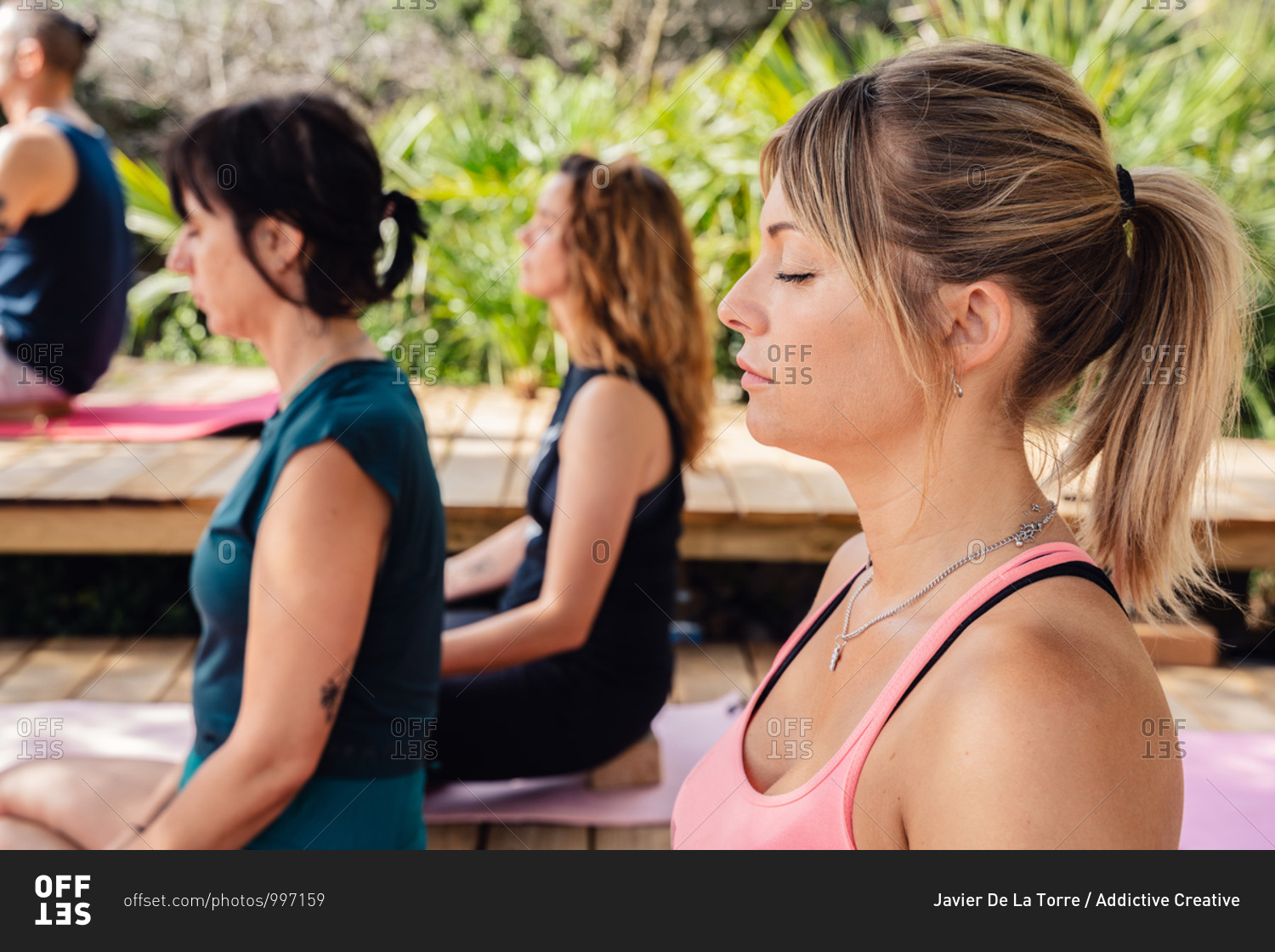 From above group of diverse people meditating in Lotus pose during yoga practice in tropical resort on sunny day