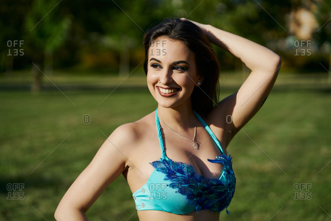 Cheerful female belly dancer performing oriental dance while standing in posture and looking away