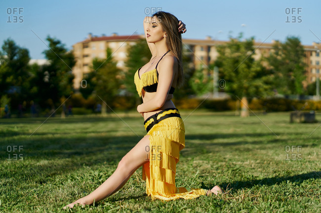 Side view of female belly dancer performing oriental dance while kneeling in posture with closed eyes