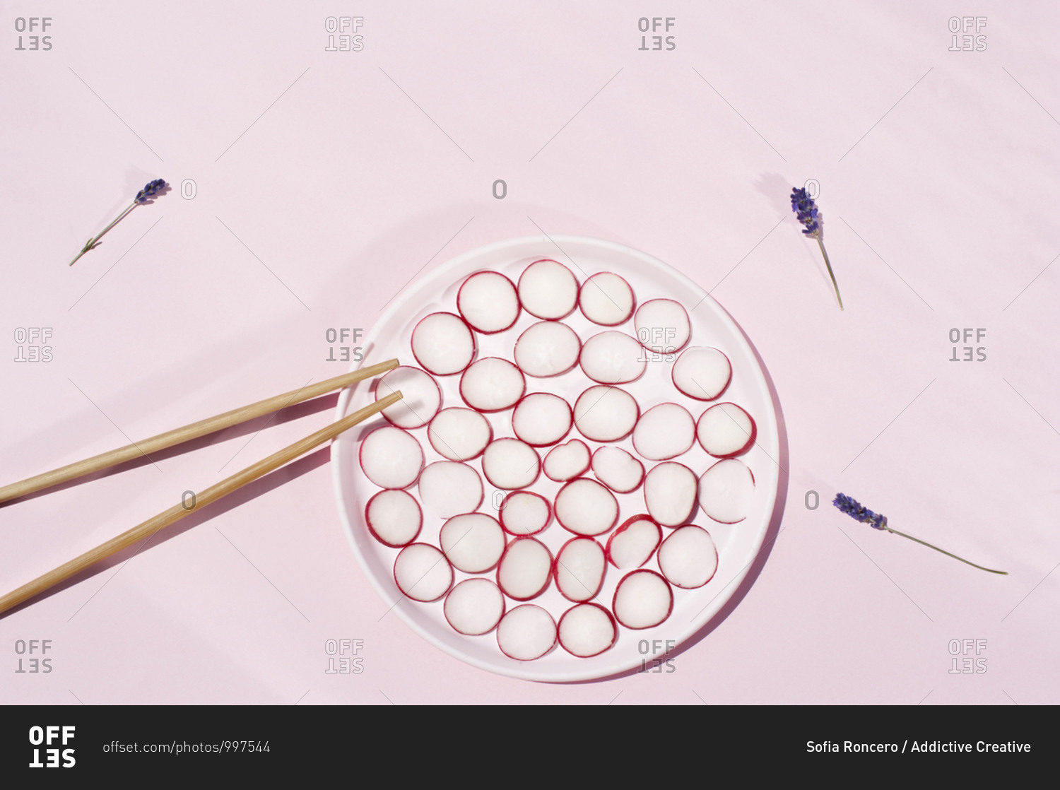 Top view of circles of fresh radish placed on plate with wooden chopsticks and lavender flowers
