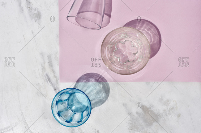From above of assorted colorful glassware casting shadow placed on pink background in studio