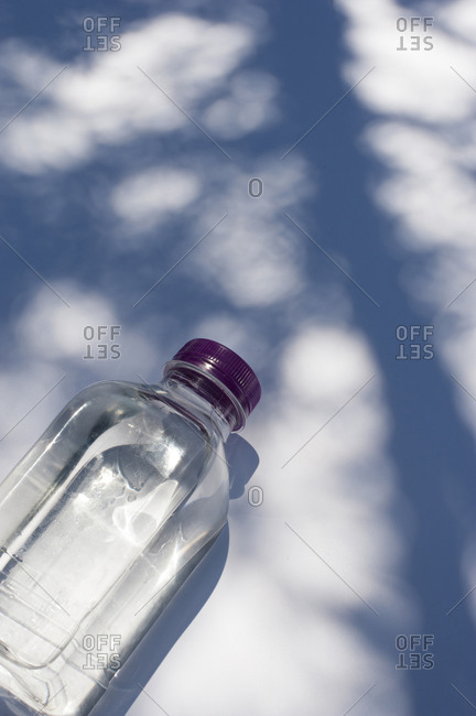 From above of fresh water in transparent plastic bottle placed on white surface with shadow