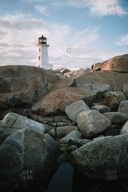 Peggys Cove Lighthouse located on stony coast against sea and cloudy sunset sky in evening in Canada