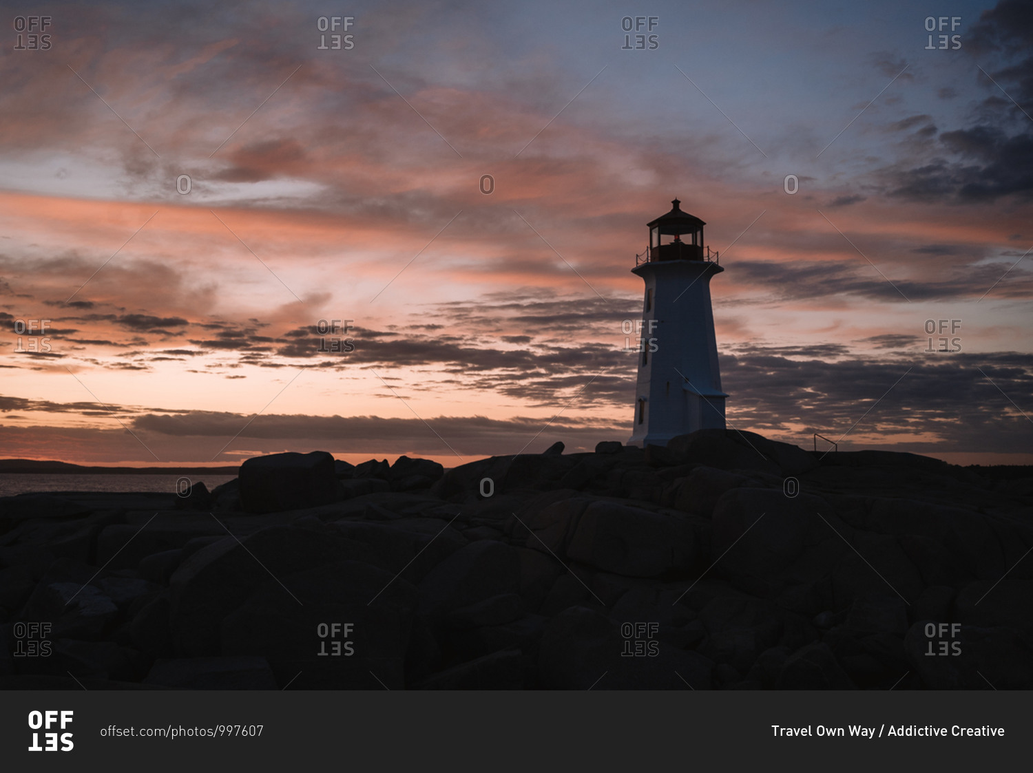 Peggys Cove Lighthouse located on stony coast against sea and cloudy sunset sky in evening in Canada