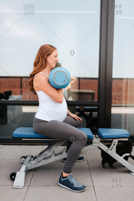 Pregnant woman using weights on balcony