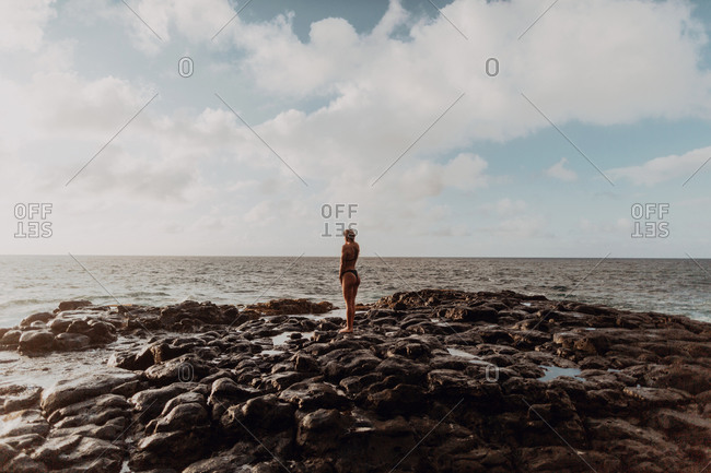 Swimmer standing on rocks by sea, Princeville, Hawaii, US