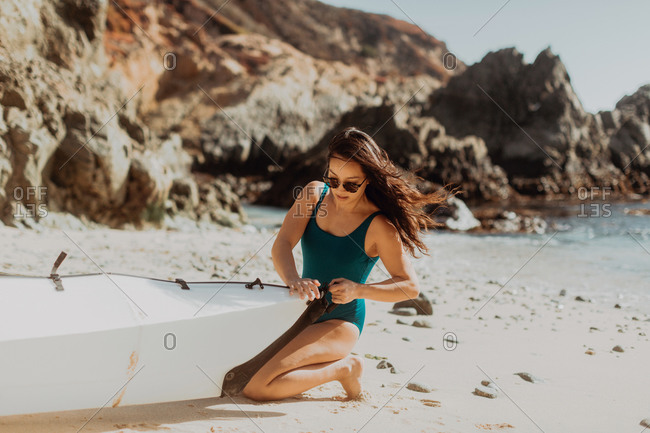 Woman preparing kayak on beach, Big Sur, California, United States