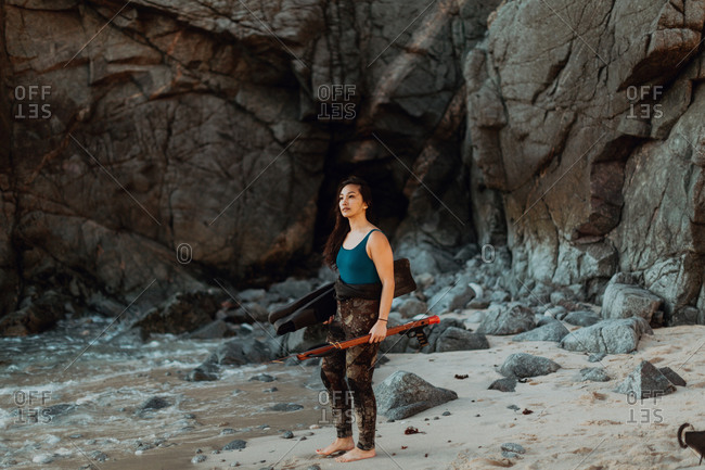 Woman with flippers and speargun on beach, Big Sur, California, United States