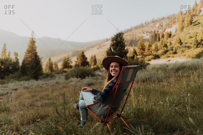 Young woman looking back from deck chair in rural valley, portrait, Mineral King, California, USA