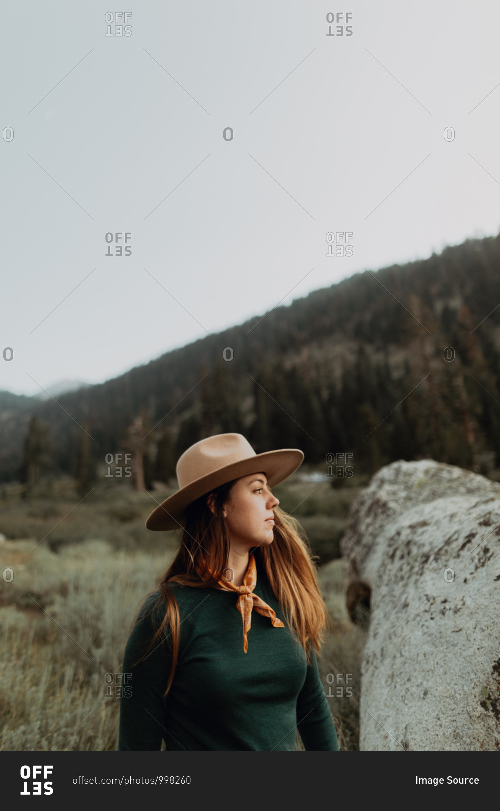 Young woman in Stetson looking over boulder in rural valley, Mineral King, California, USA