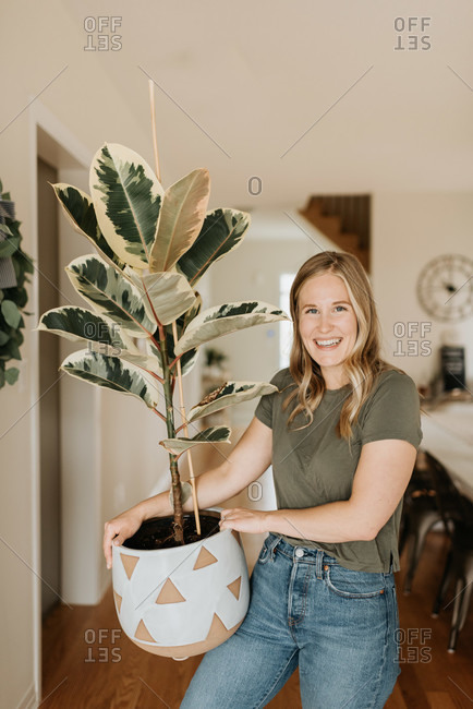 Woman carrying large pot of house plant