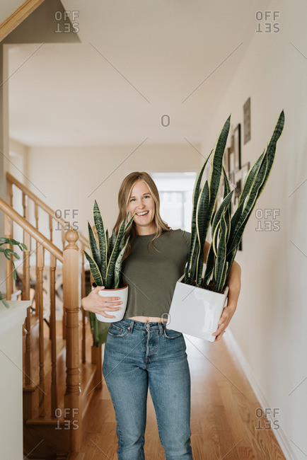 Woman carrying large and small pots of house plant