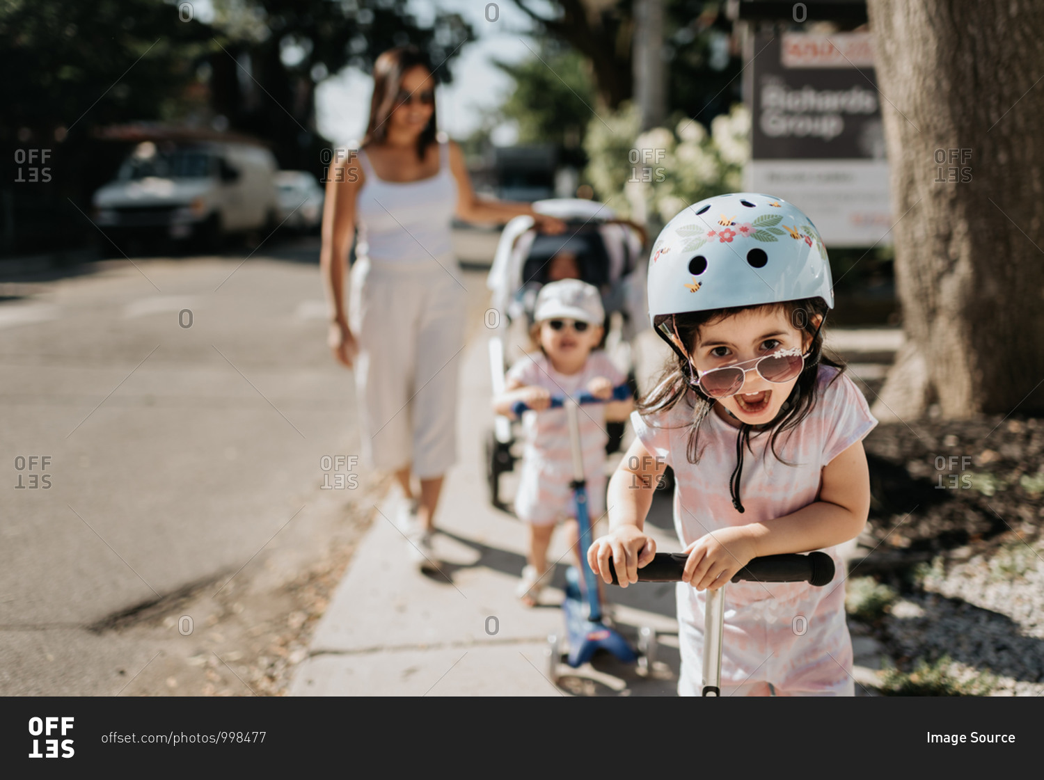 Mother and daughters playing push scooter in neighborhood