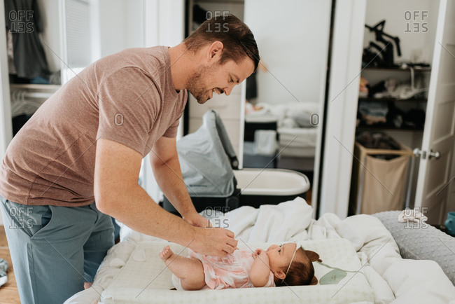 Father changing diaper of baby girl on changing table