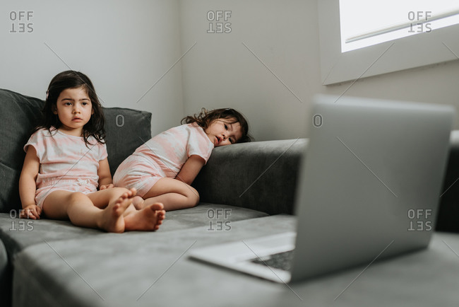 Sisters relaxing in front of laptop on couch
