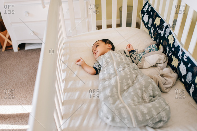 Baby boy lying awake in crib, high angle view