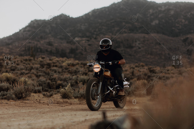 Motorbiker riding through landscape of Kennedy Meadows, California, US