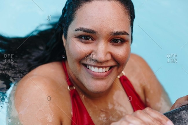 Mid adult woman with wet hair holding onto outdoor swimming poolside, head and shoulder portrait, Cape Town, South Africa