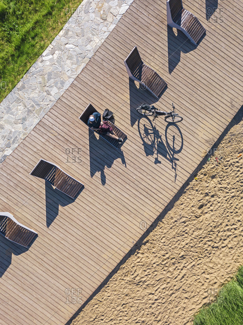 Russia- Tikhvin- Man with bicycle on boardwalk with sun loungers- aerial view