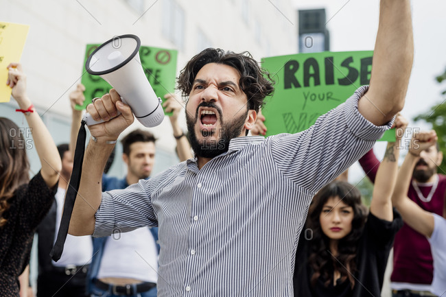 Man holding megaphone screaming with protestors on street