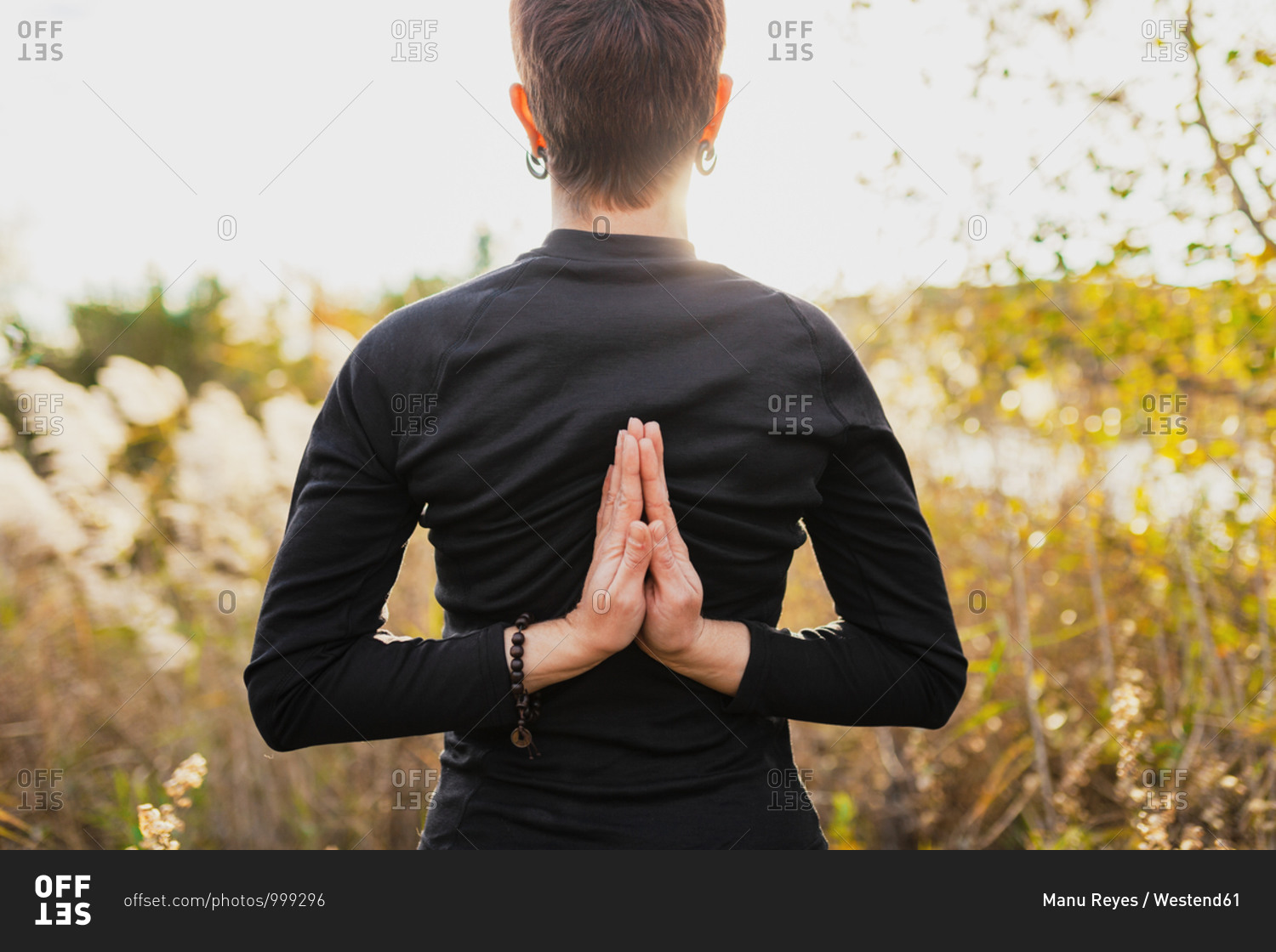 Woman practicing reverse prayer position while standing outdoors
