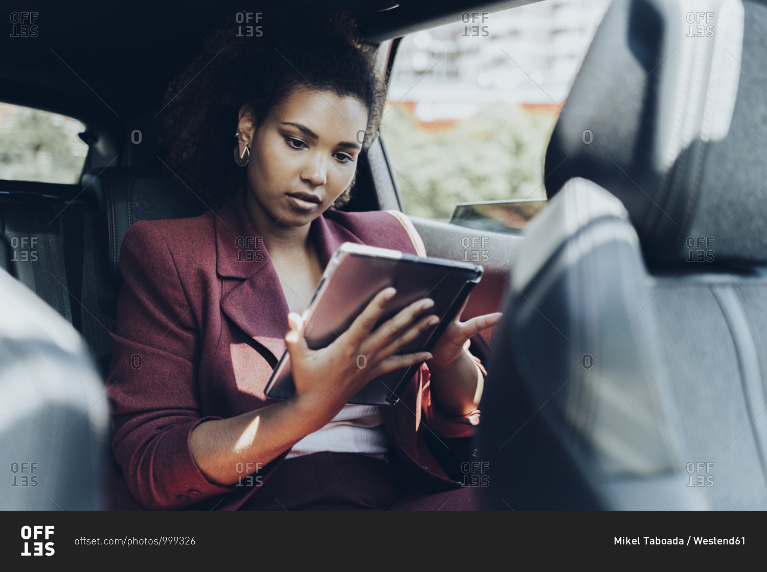 Young female entrepreneur using digital tablet while sitting in car