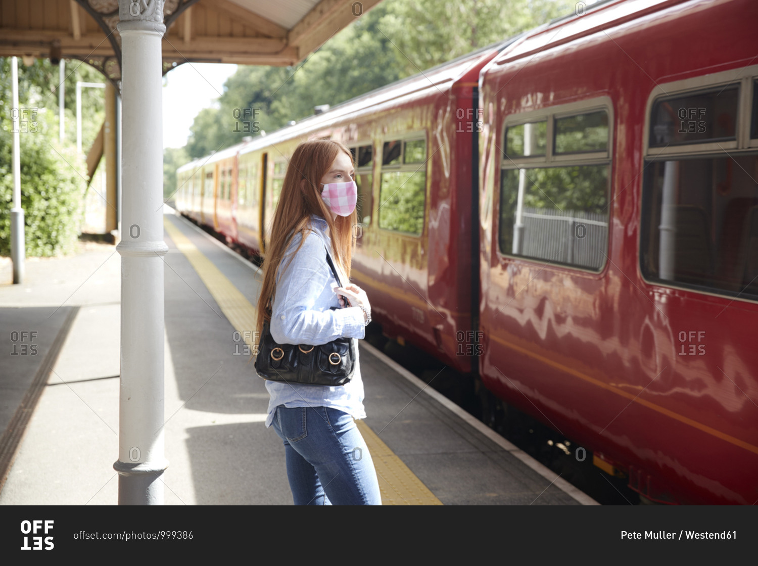 Young woman wearing protective face mask while standing at
railroad station platform stock photo - OFFSET