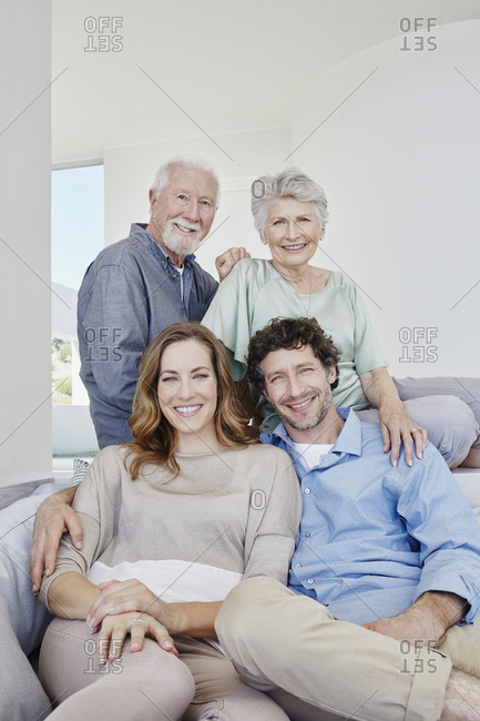 Portrait of happy senior couple with adult children sitting on a couch in a villa