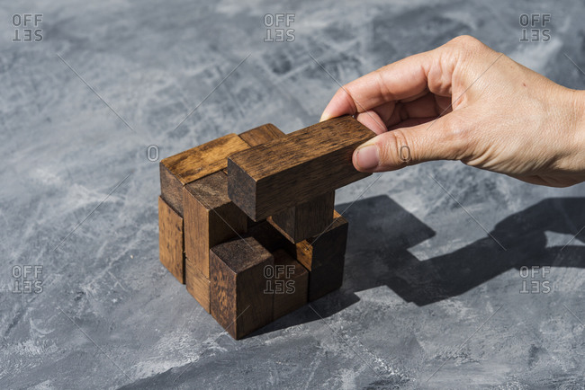 Hand of woman assembling pieces of wooden puzzle