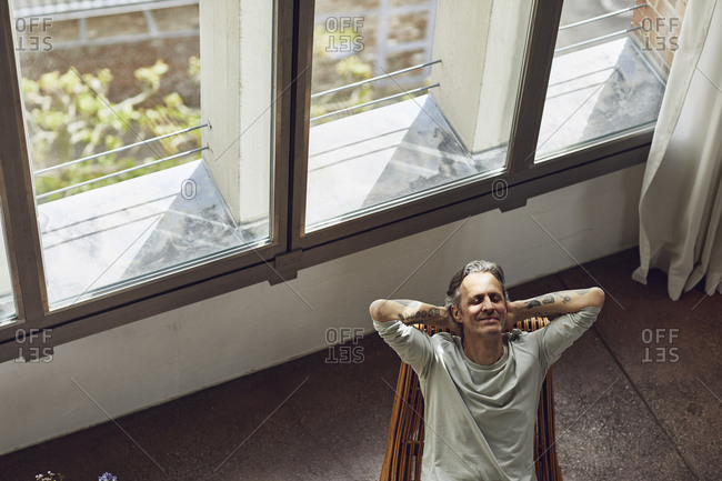 Senior man looking out of window in a loft flat stock photo