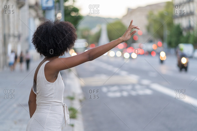 Young African-American woman in a hipster dress trying to stop a taxi