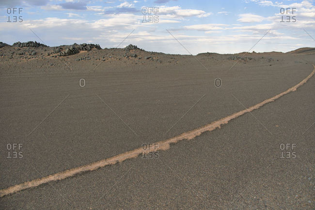 Scenery view of desert with sandy dunes with shabby surface with wheel marks