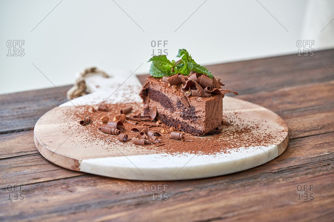 Delectable halved chocolate mousse cake with garnished with fresh mint leaves served on wooden board on table