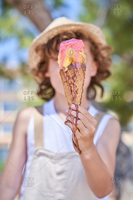 Selective focus of melting berry and vanilla ice cream in waffle cone in arms of delight boy