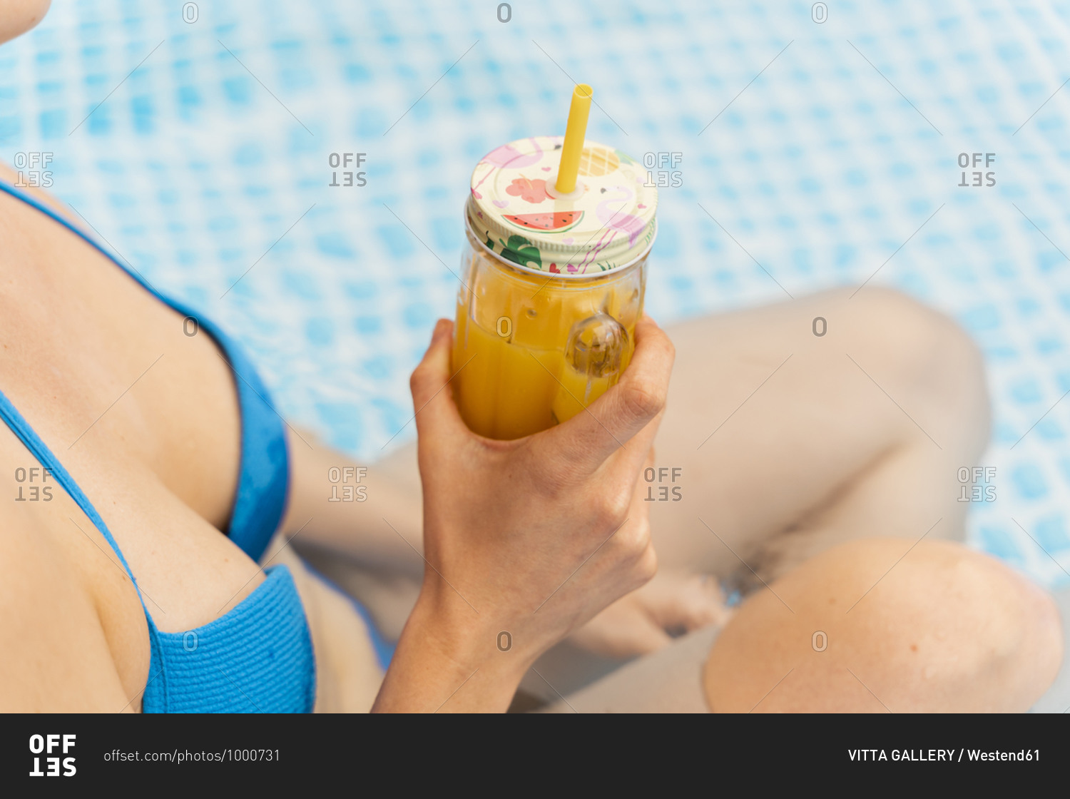 Sensuous woman holding orange juice in inflatable swimming pool at yard