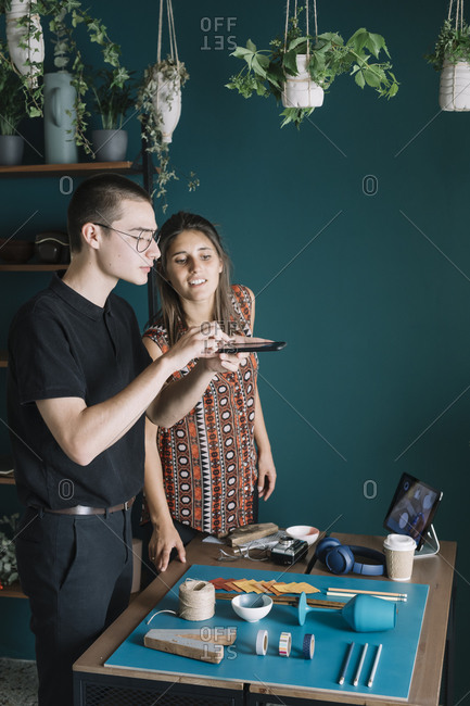 Young creative couple taking smartphone picture of decoration on table