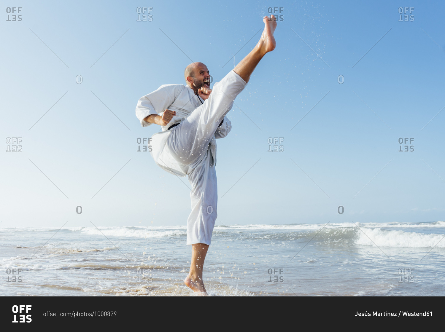 Man screaming while practicing karate in sea against clear sky