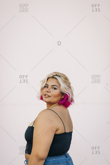 Plus size woman standing against pink wall
