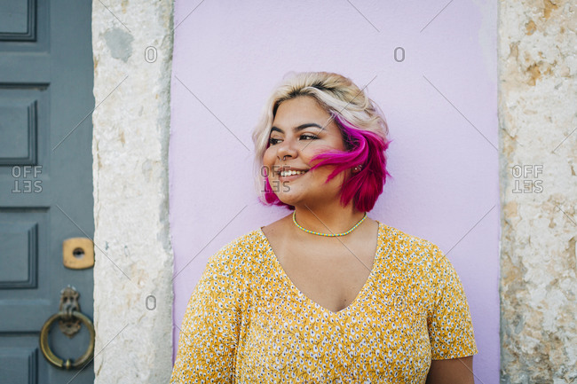 Smiling plus size woman standing against wall