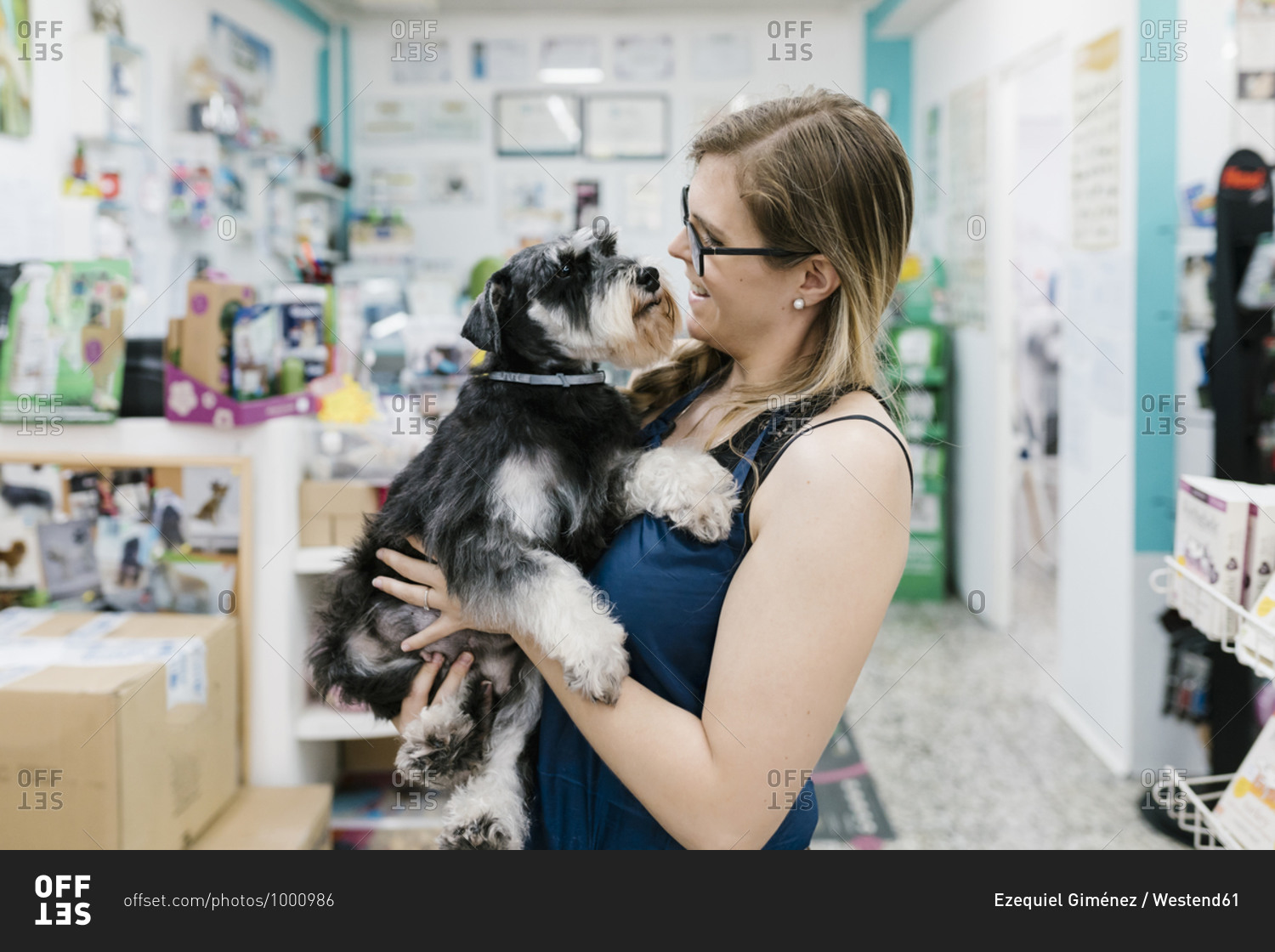Happy woman carrying schnauzer while standing in pet salon