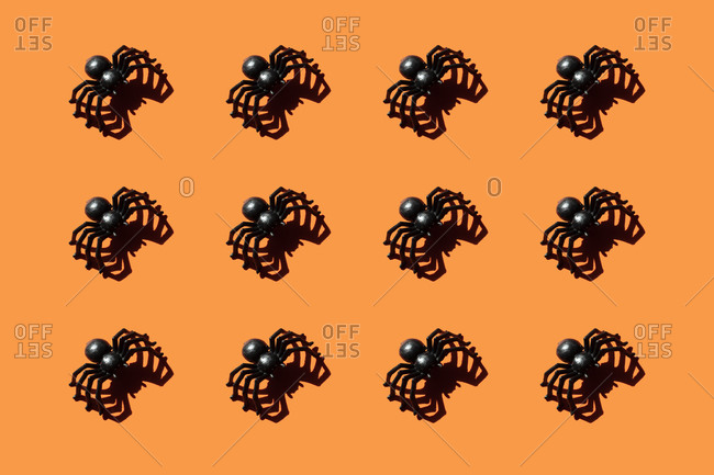 Pattern of black plastic spiders against orange background