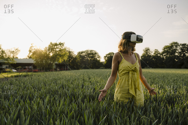 Young woman wearing VR goggles in a grain field in the countryside